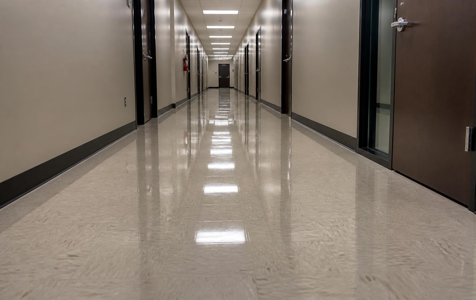 The same corridor floor with a high-gloss finish after stripping and refinishing